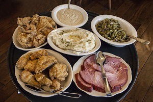 Fried chicken, mashed potatoes, ham, green beans and gravy on a serving tray