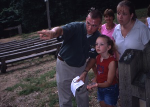 a park naturalist points out something to a family during an evening nature program