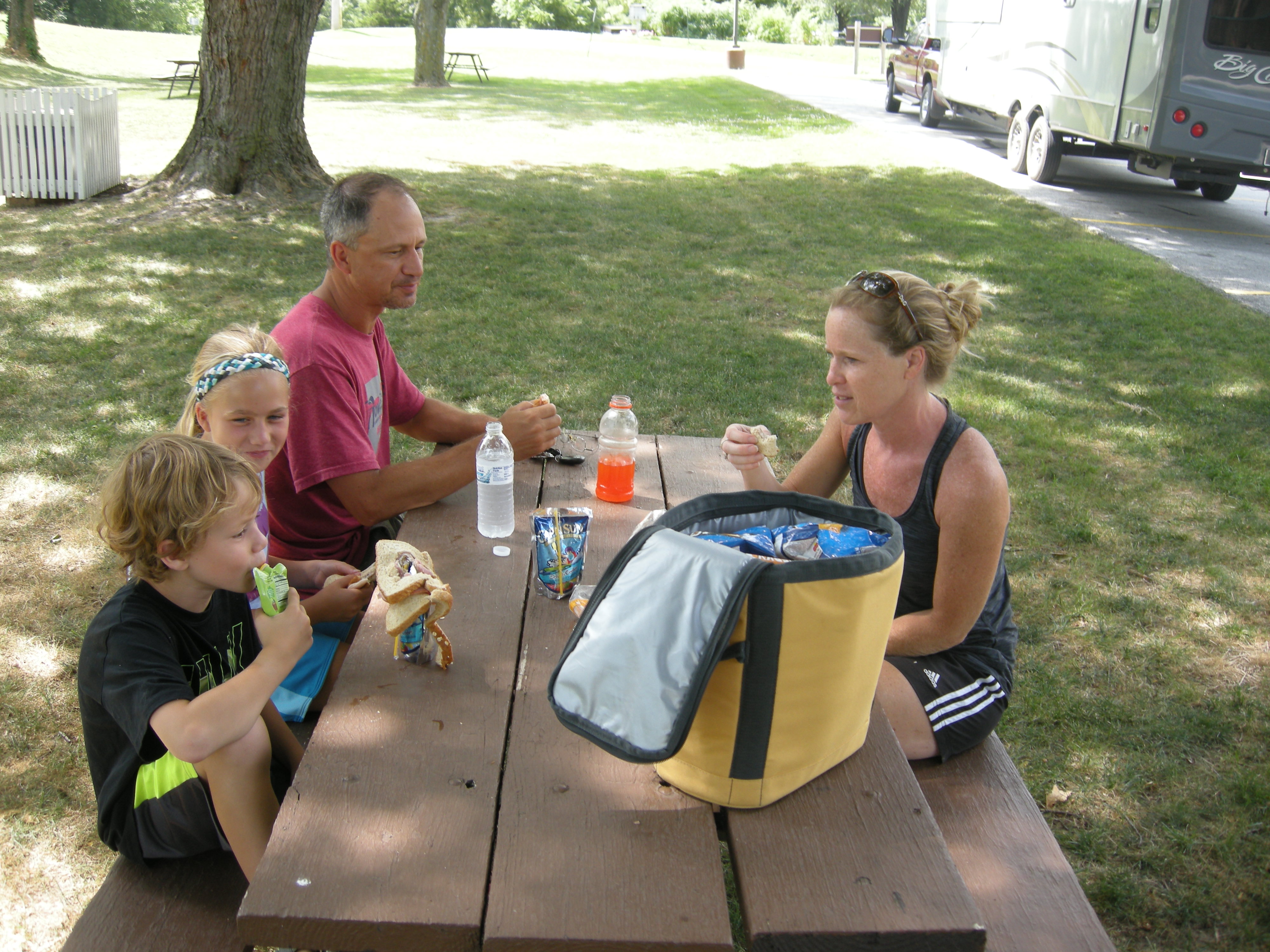 A family enjoys lunch at a picnic table