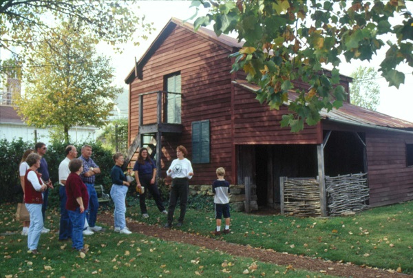 A tour group in front of an old barn at Deutschheim State Historic Site