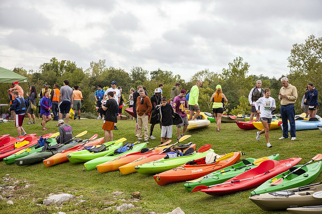 a row of colorful kayaks and people ready to participate in an event
