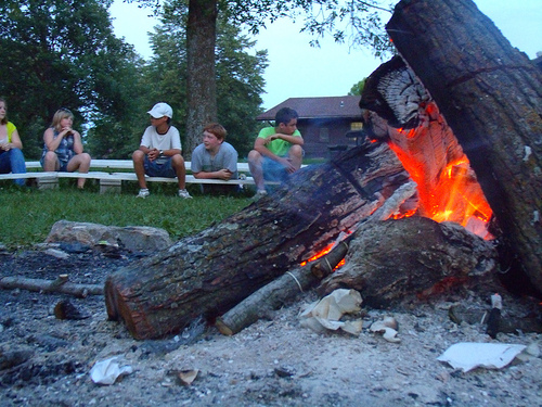 Kids sitting around a group fire ring. 