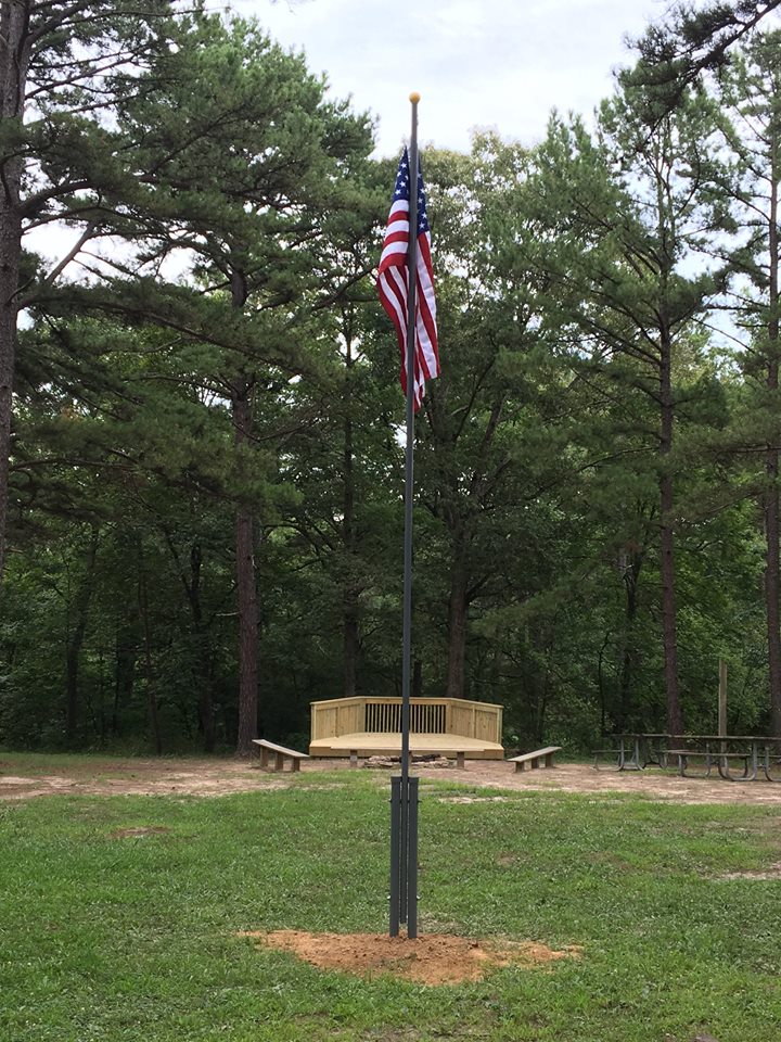 flag pole with flag and group fire ring area in the background