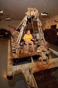 a kid sitting on a piece of the  old mining equipment