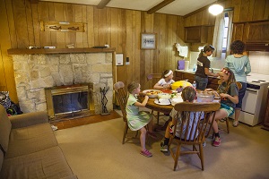 a family eating at the table inside one of the cabins, which has a fireplace