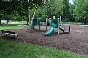 a bench sitting next to playground equipment with two slides