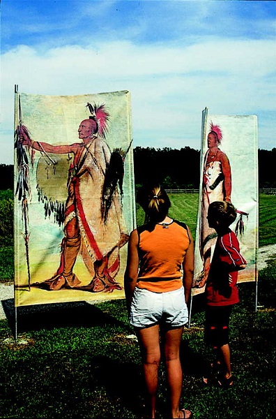 two kids look at flags that show images of Osage Indians