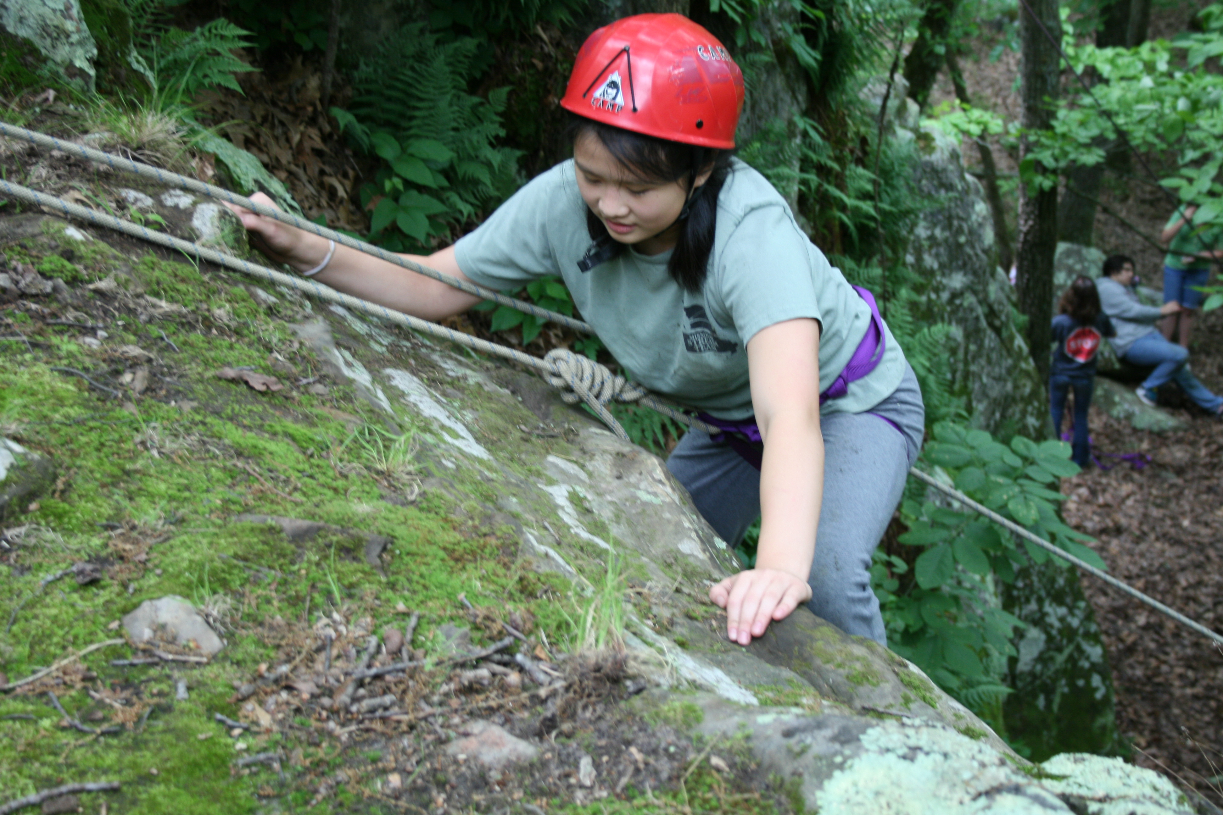 A girl rappelling down a bluff