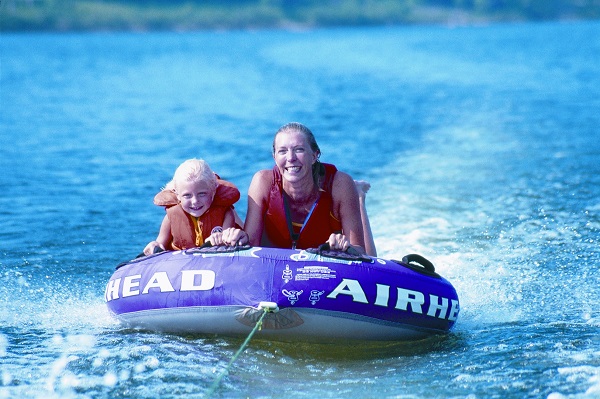 a mother and daughter being pulled on a tube on the lake