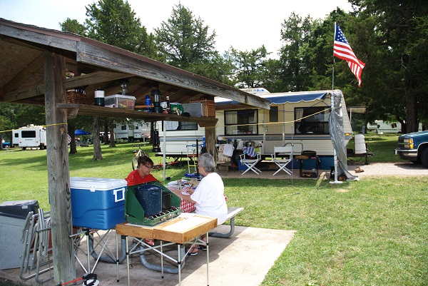 a couple sitting at a sheltered picnic table in front of their camper