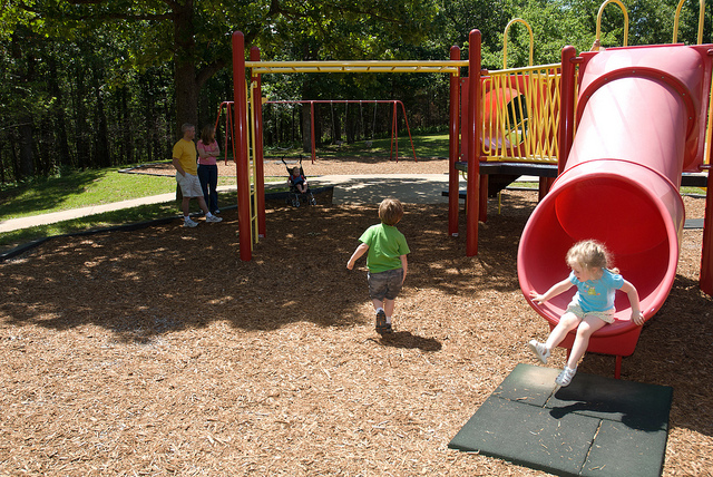 toddlers playing on playground equipment with slides and monkey bars