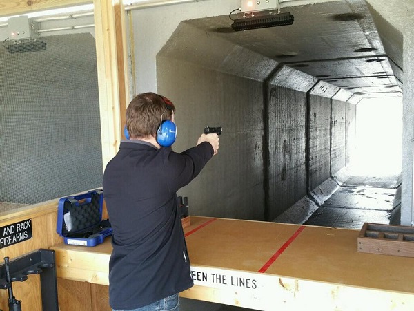 A man shooting a gun at a target at the shooting range. 