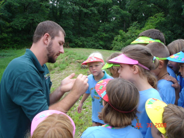 a naturalist showing a group of kids something in his hand