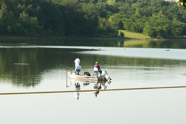 two people fishing from a boat on the lake