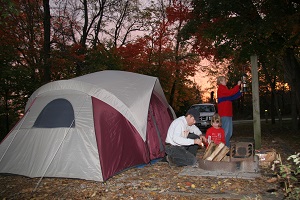 a man and boy building a campfire in front of their tent