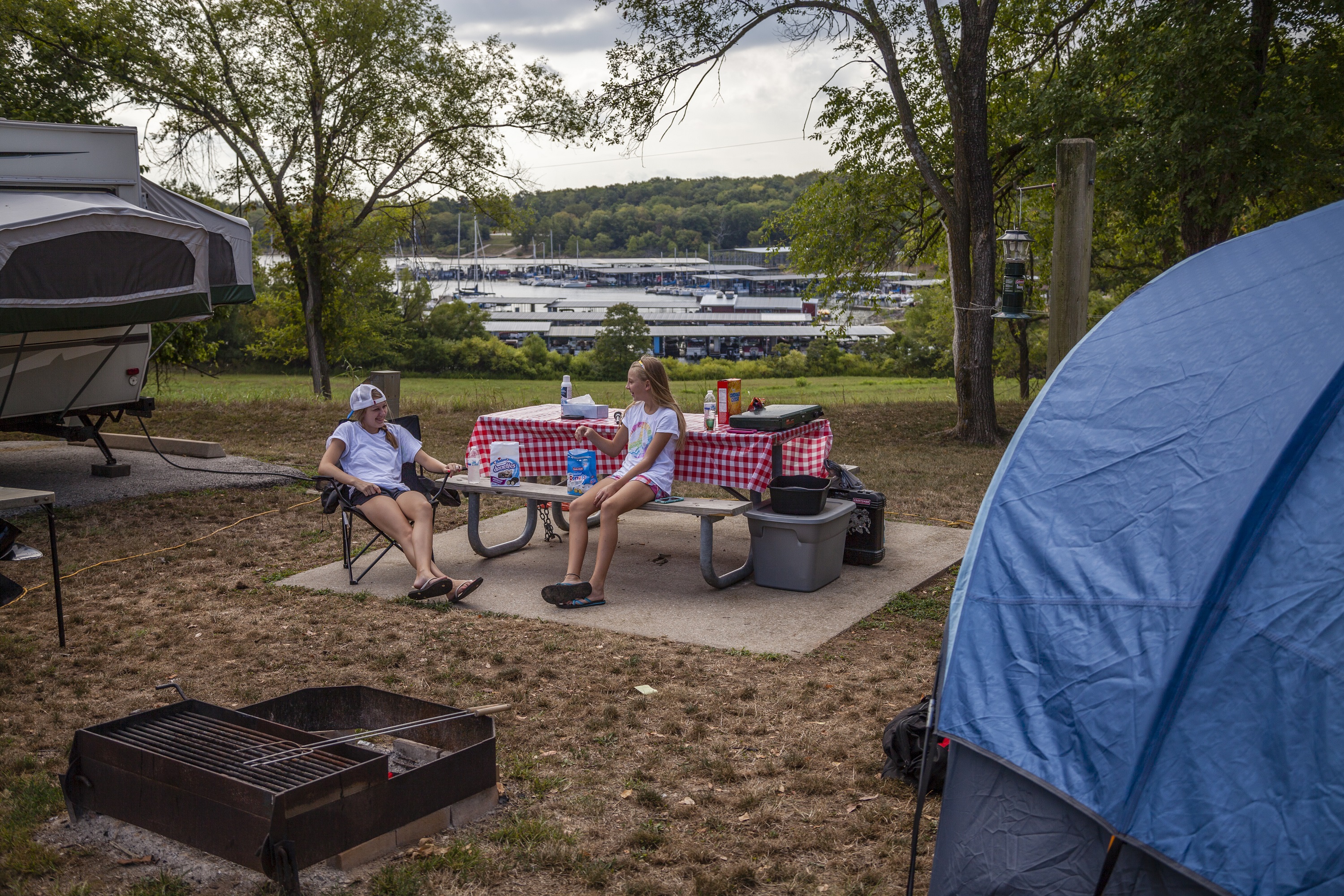 Two kids sitting at a picnic table in a camp grounds