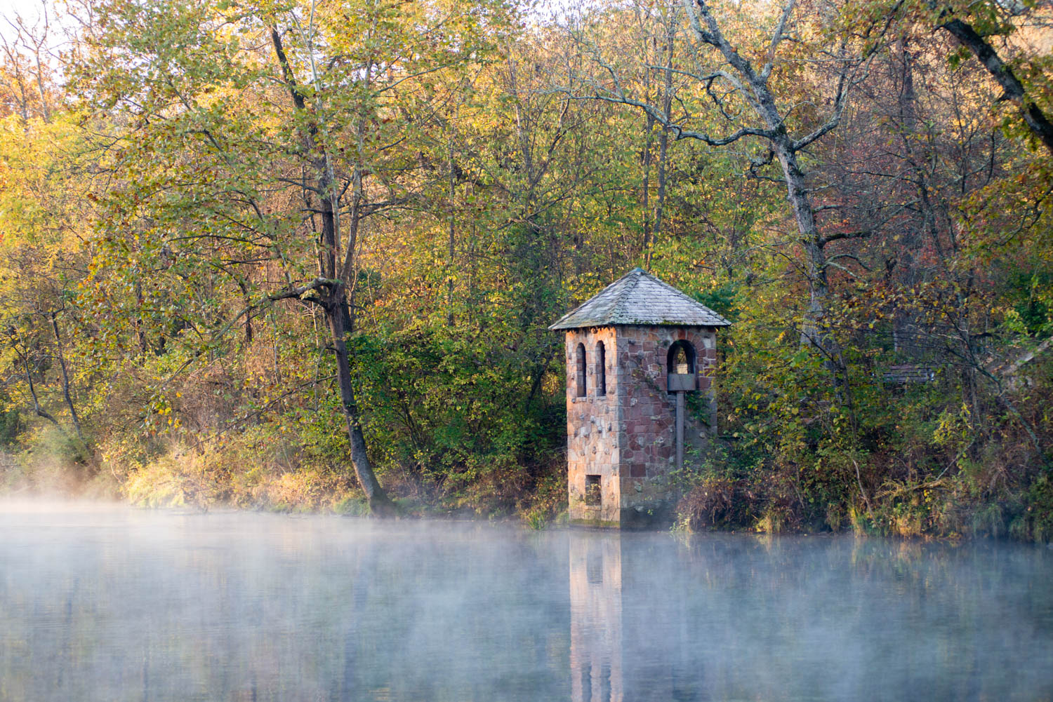 an old brick tower on the edge of a river