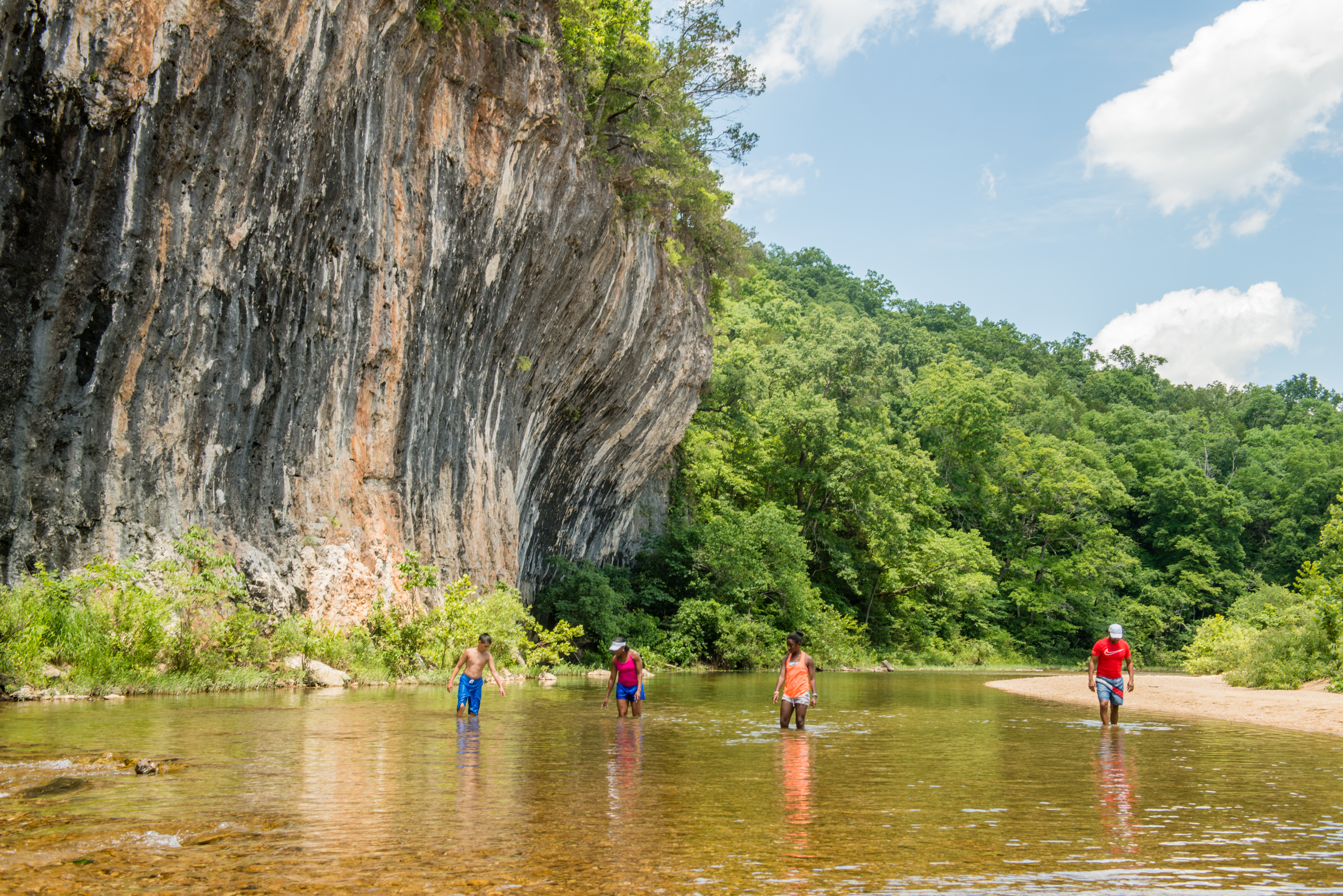 People in a river by a cliffside