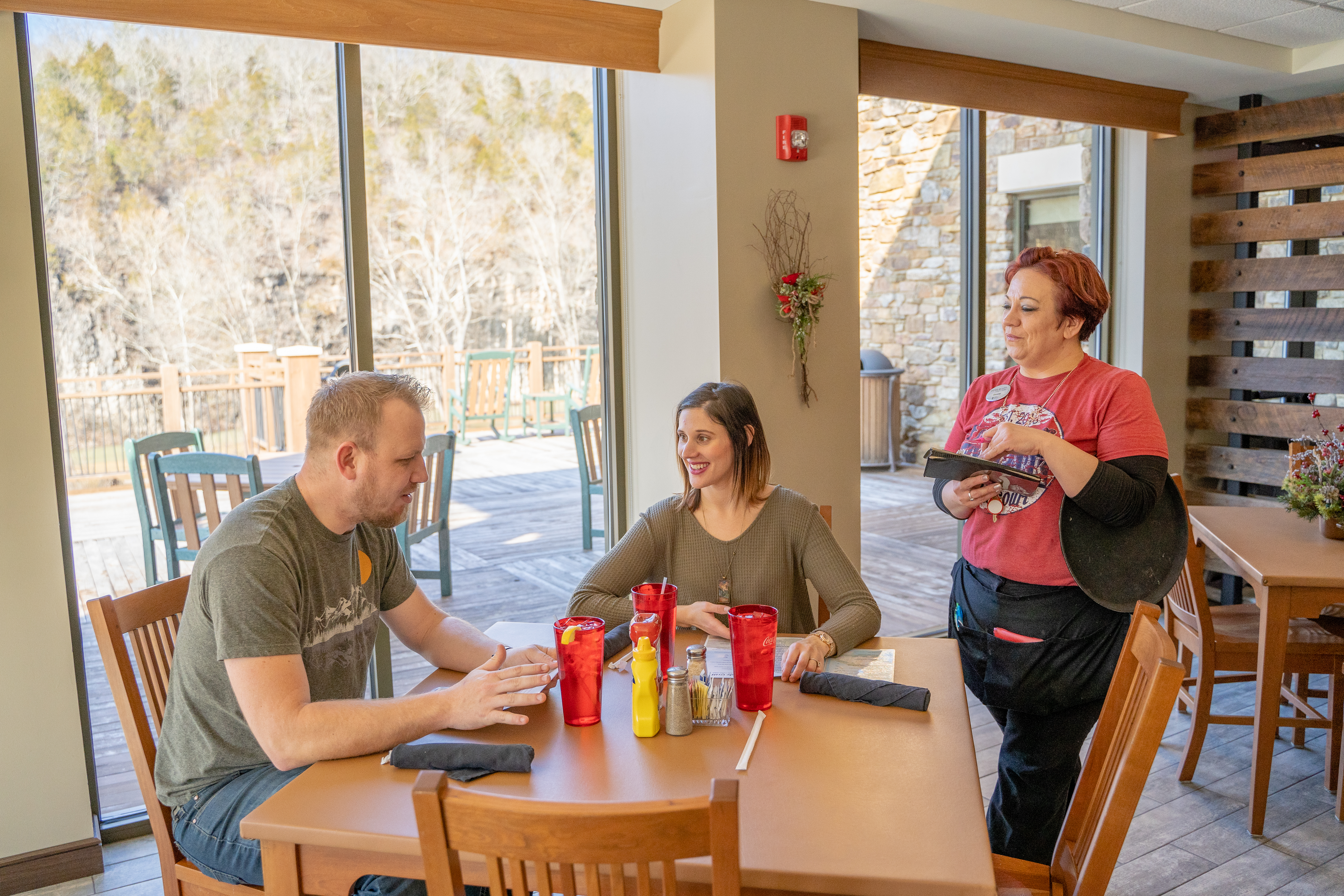 two people sitting at a table with a waitress taking their orders