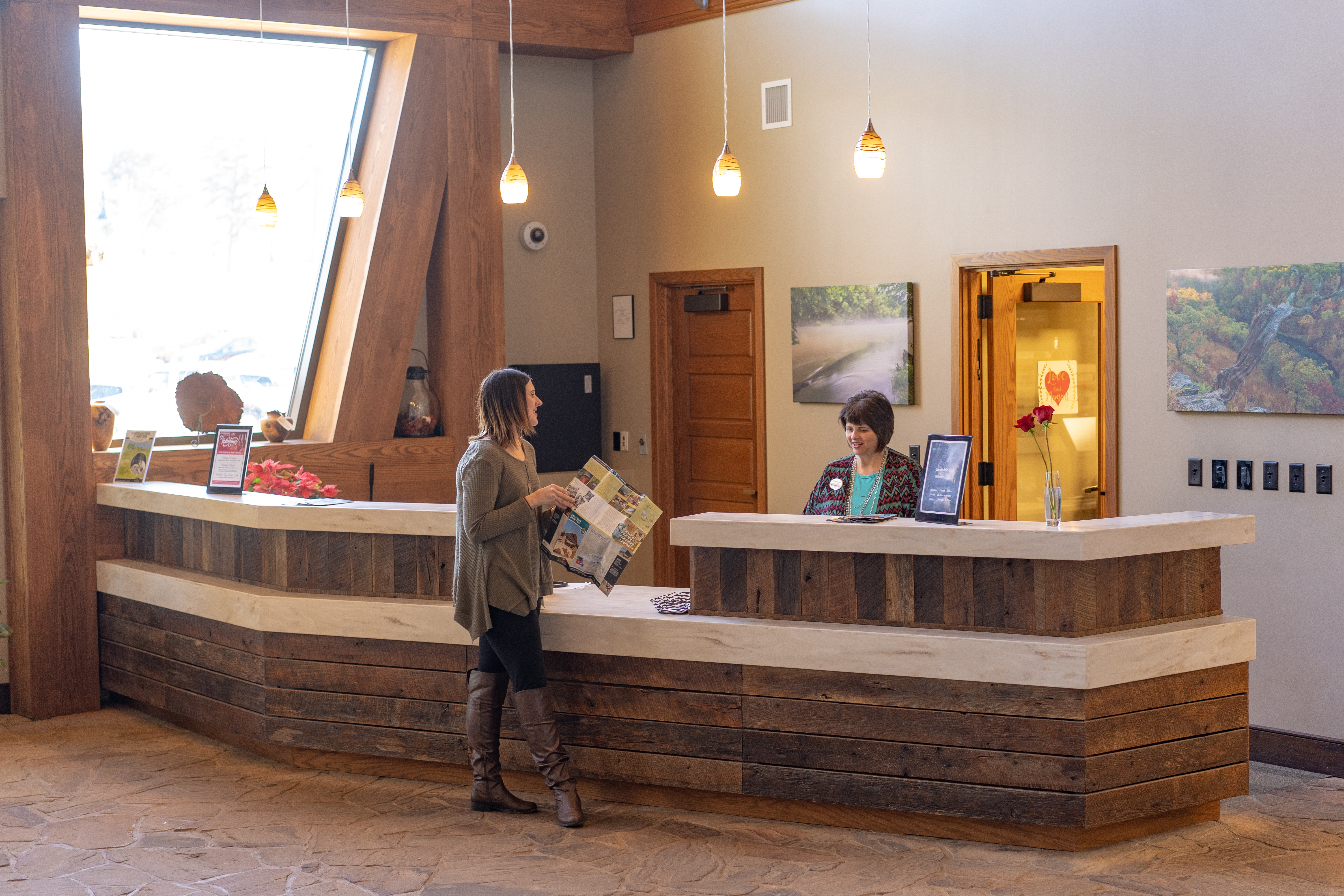 a woman with a brochure at a receptionist desk with another woman with a name tag behind it