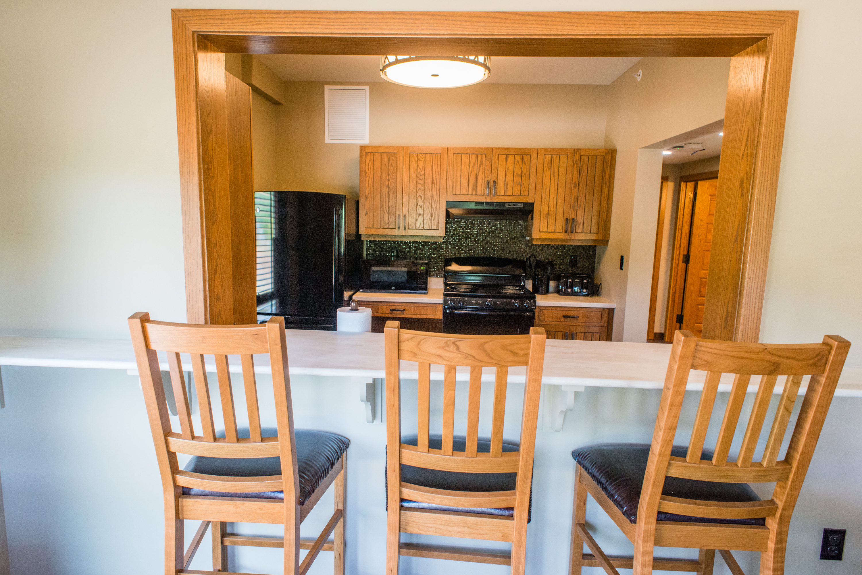 a counter with barstools looking into a full kitchen