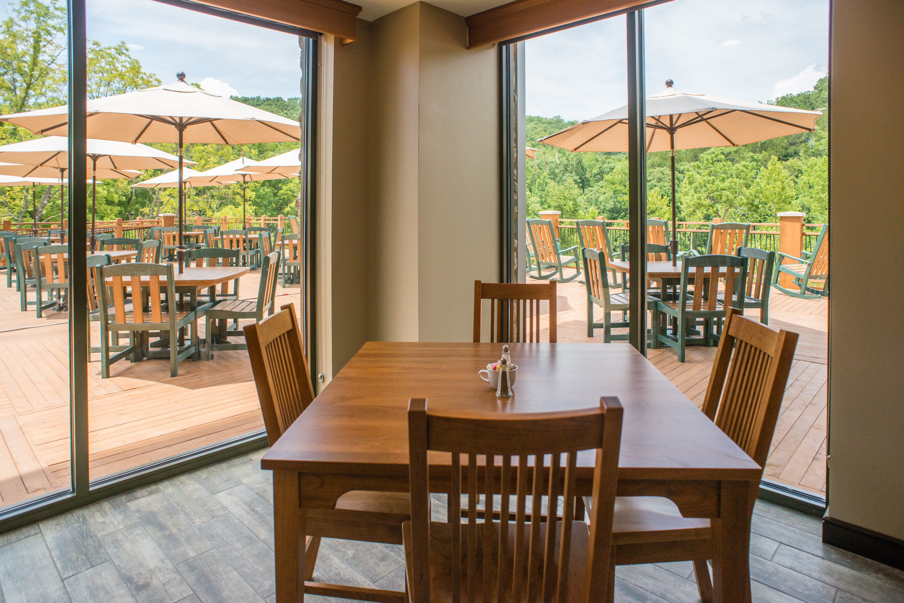 a dining room with windows looking out onto a deck with more seating and chairs looking over the edge