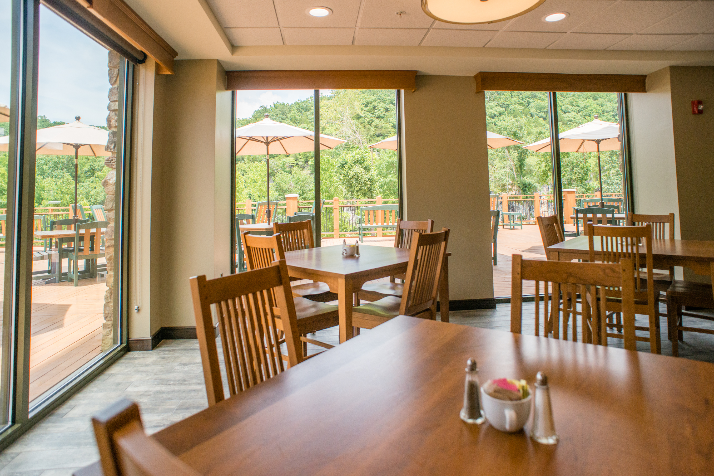a dining room with windows looking out onto a deck with more seating