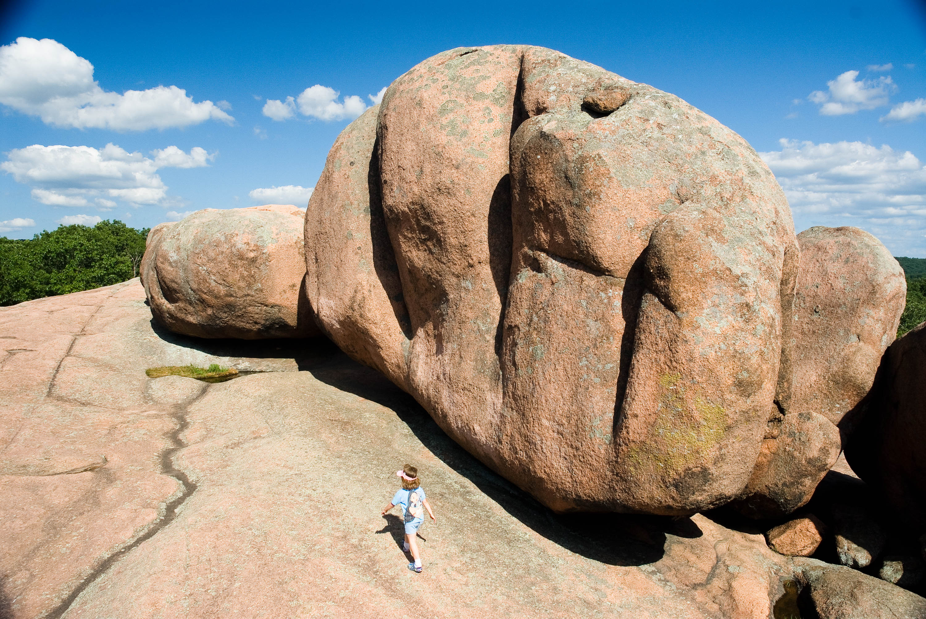 a person hiking next to a very large rock