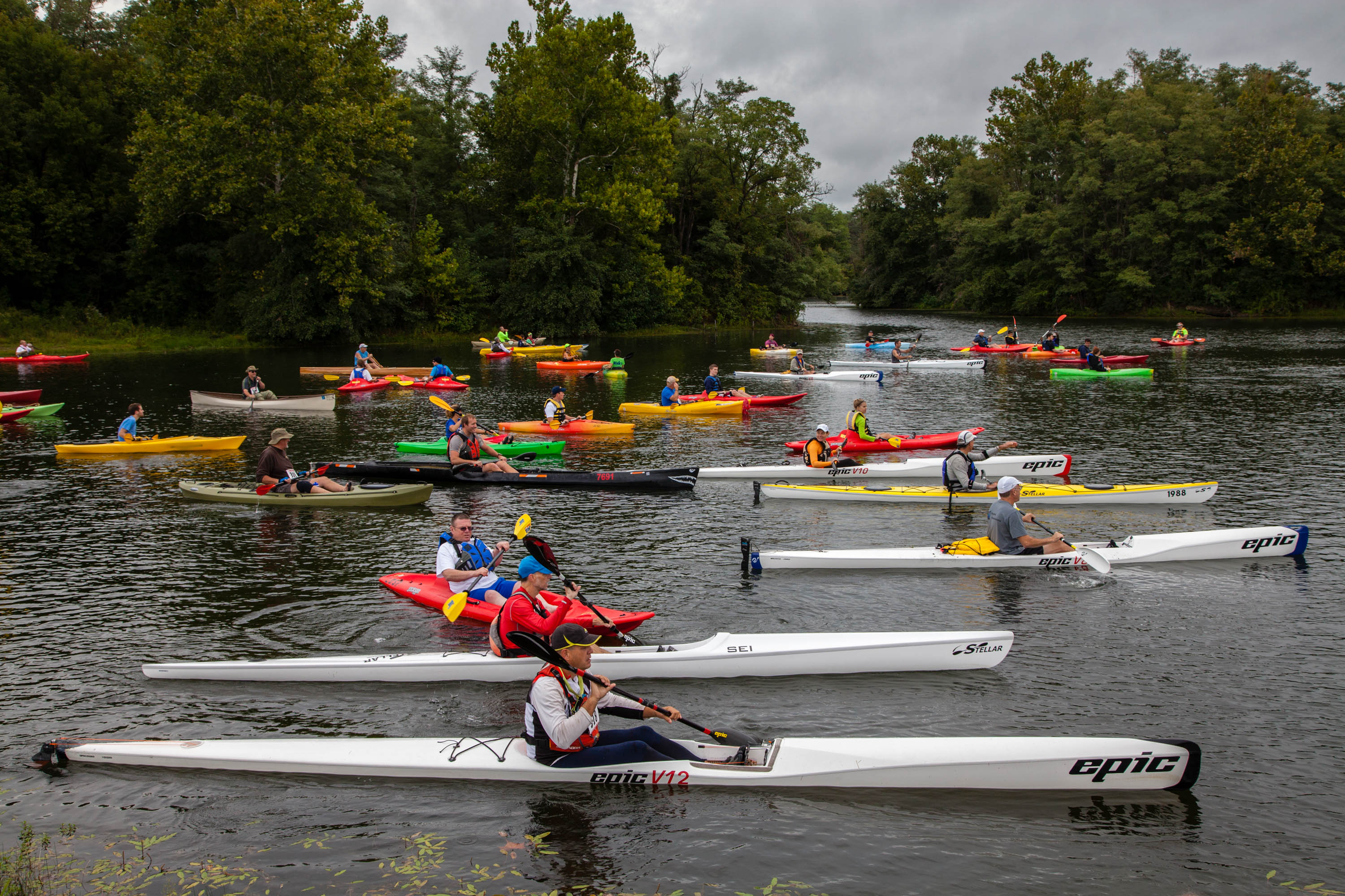 many people on multi-color kayaks in a lake