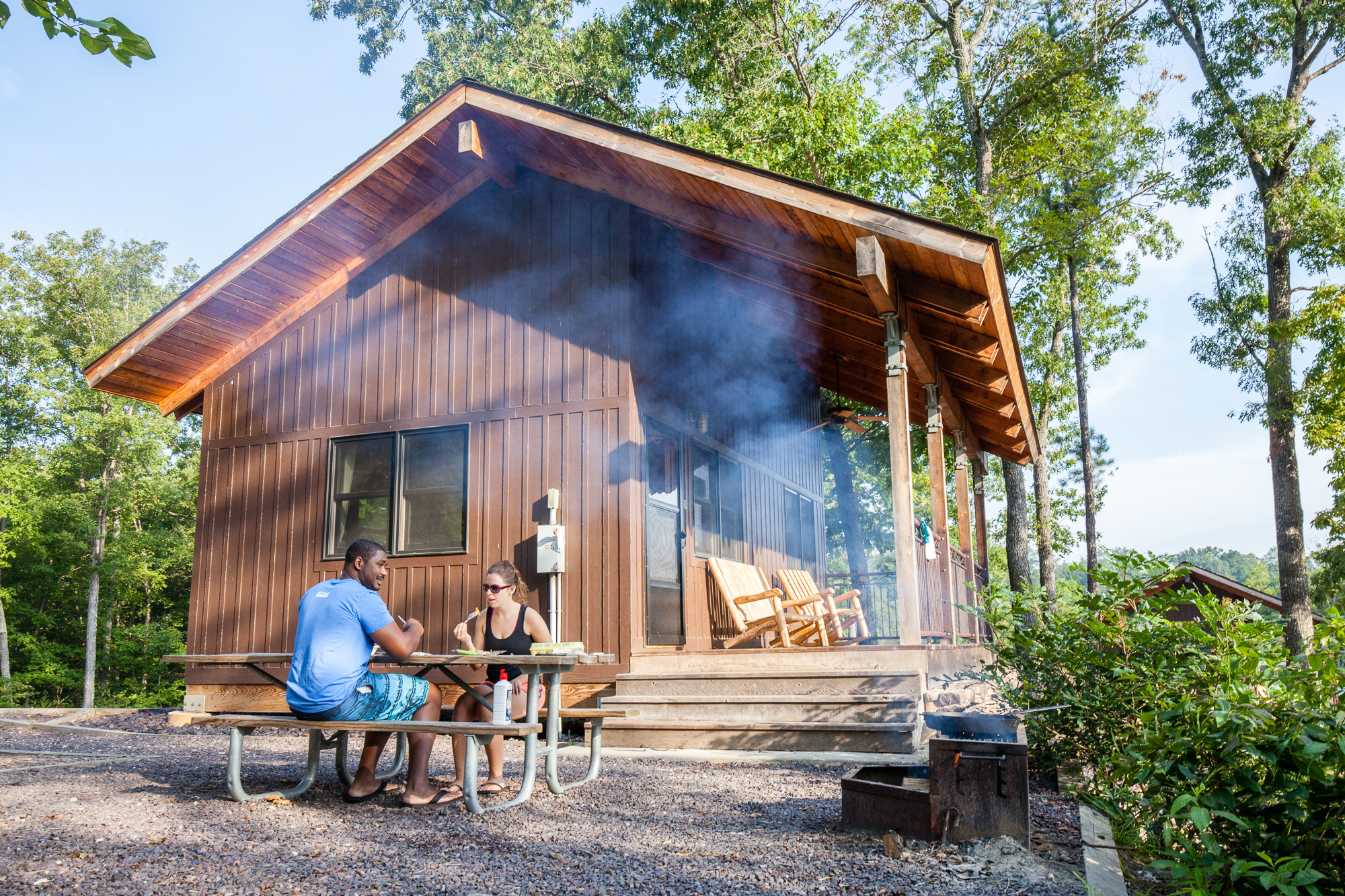 People grilling next to a cabin