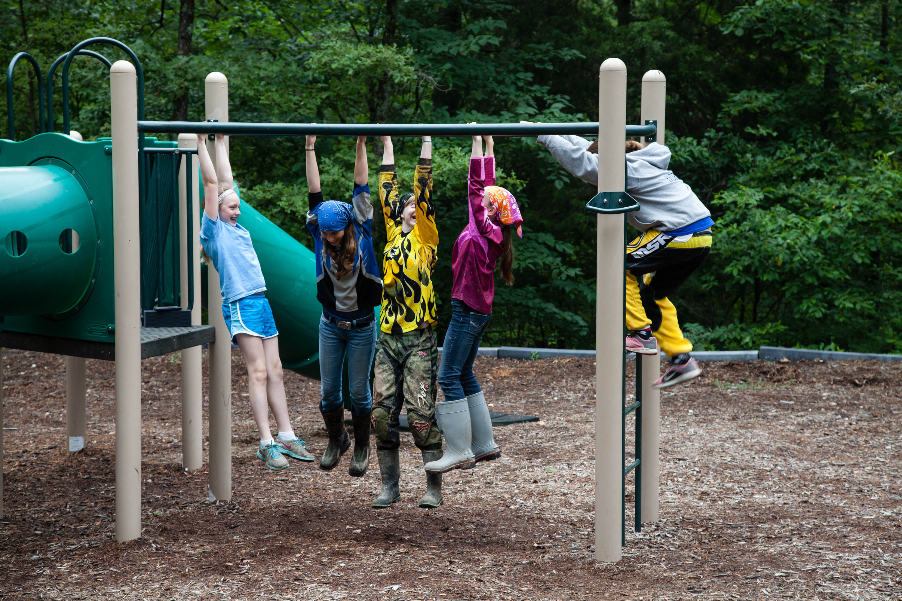 Five kids hanging on a set of monkey bars