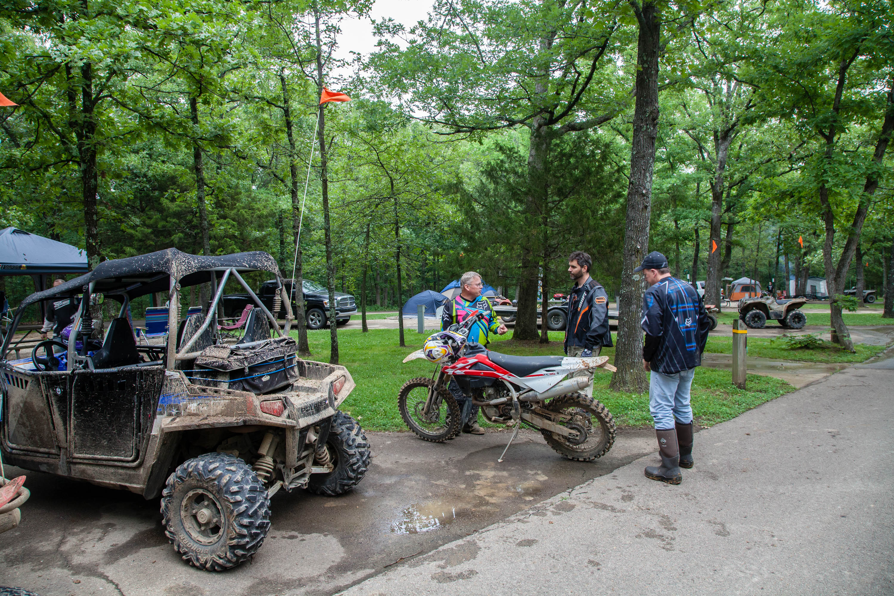 Three men talking around a dirt bike