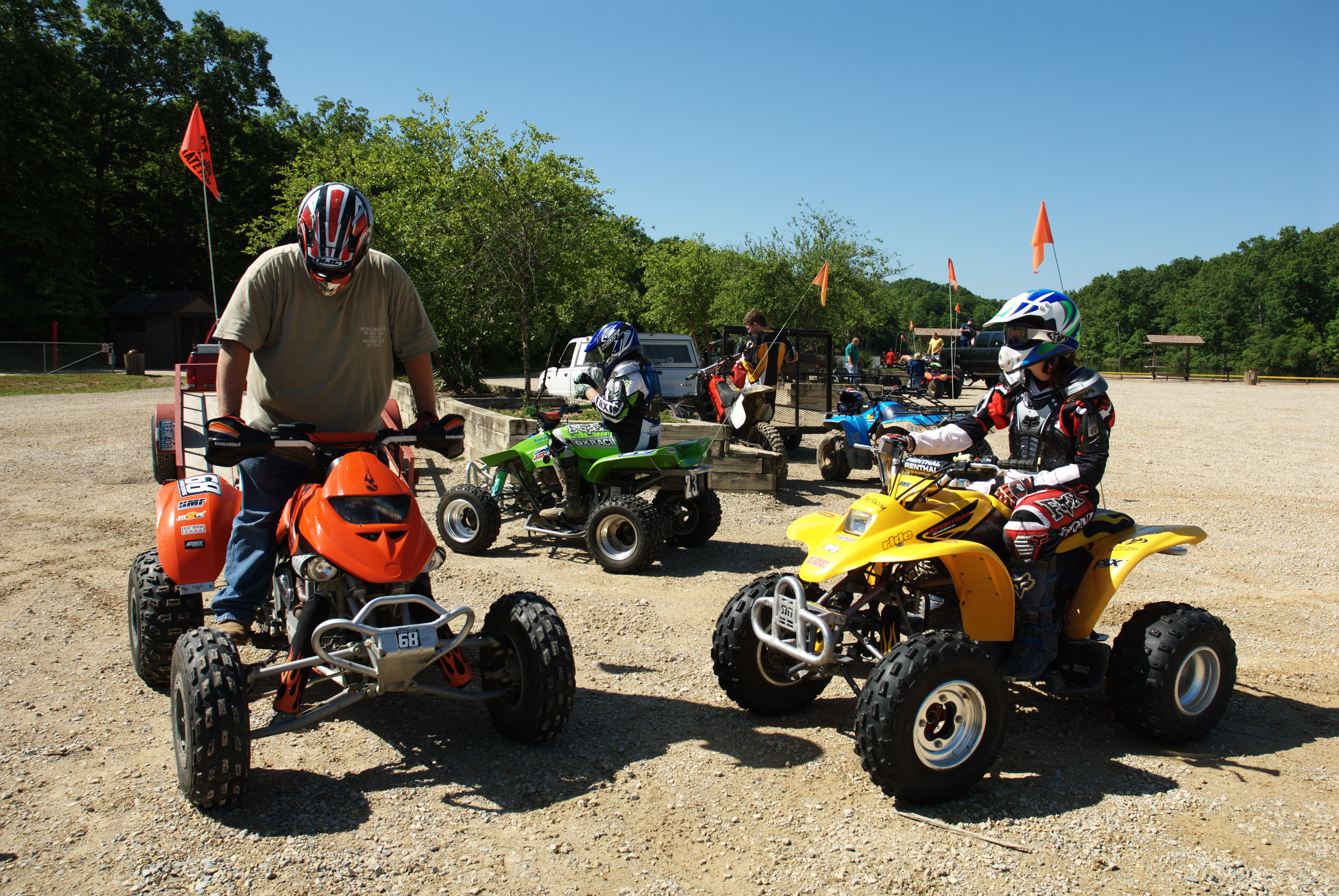 Three people on four wheelers, red, green, and yellow