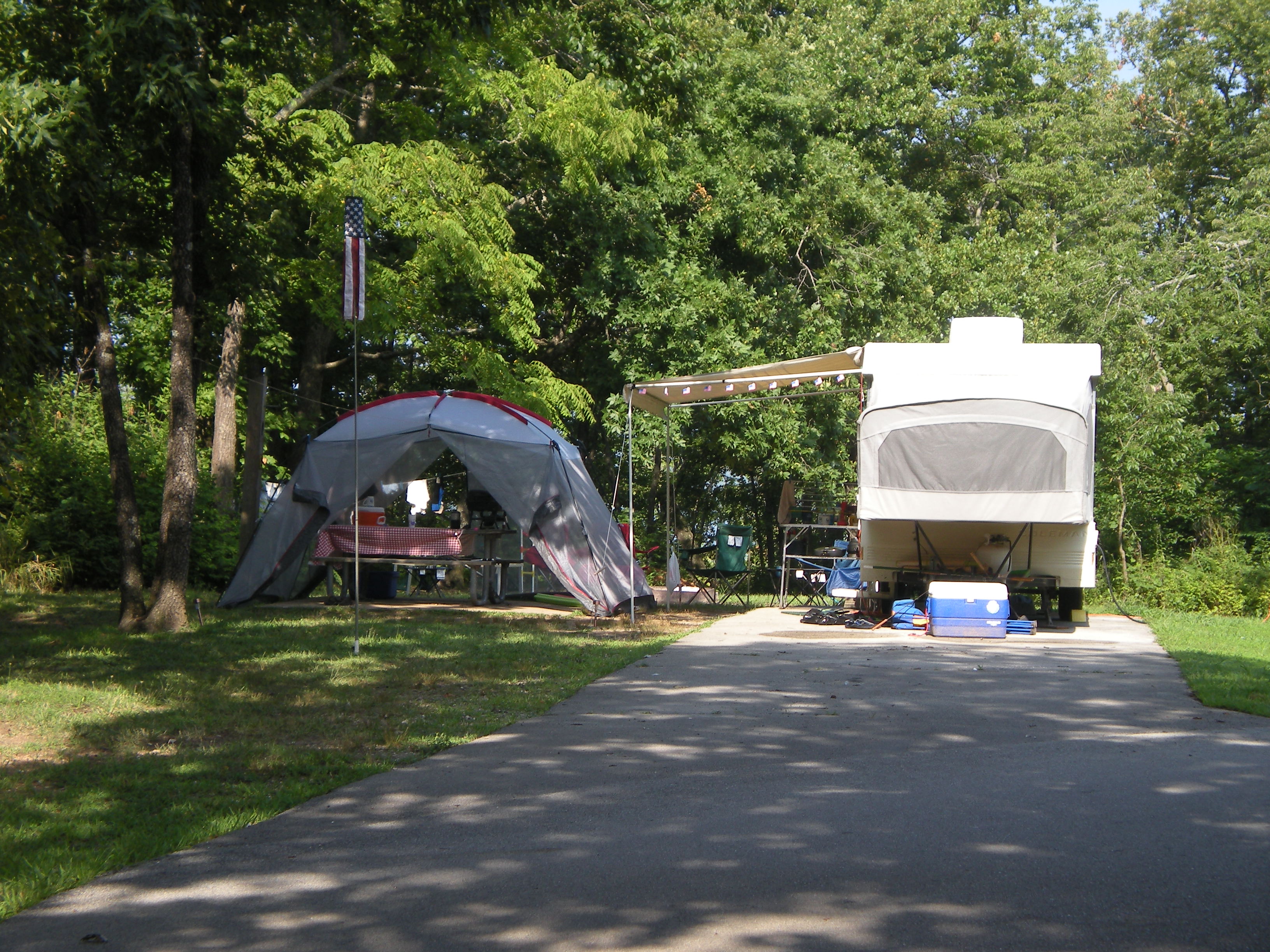 A picnic tent set up next to a camper