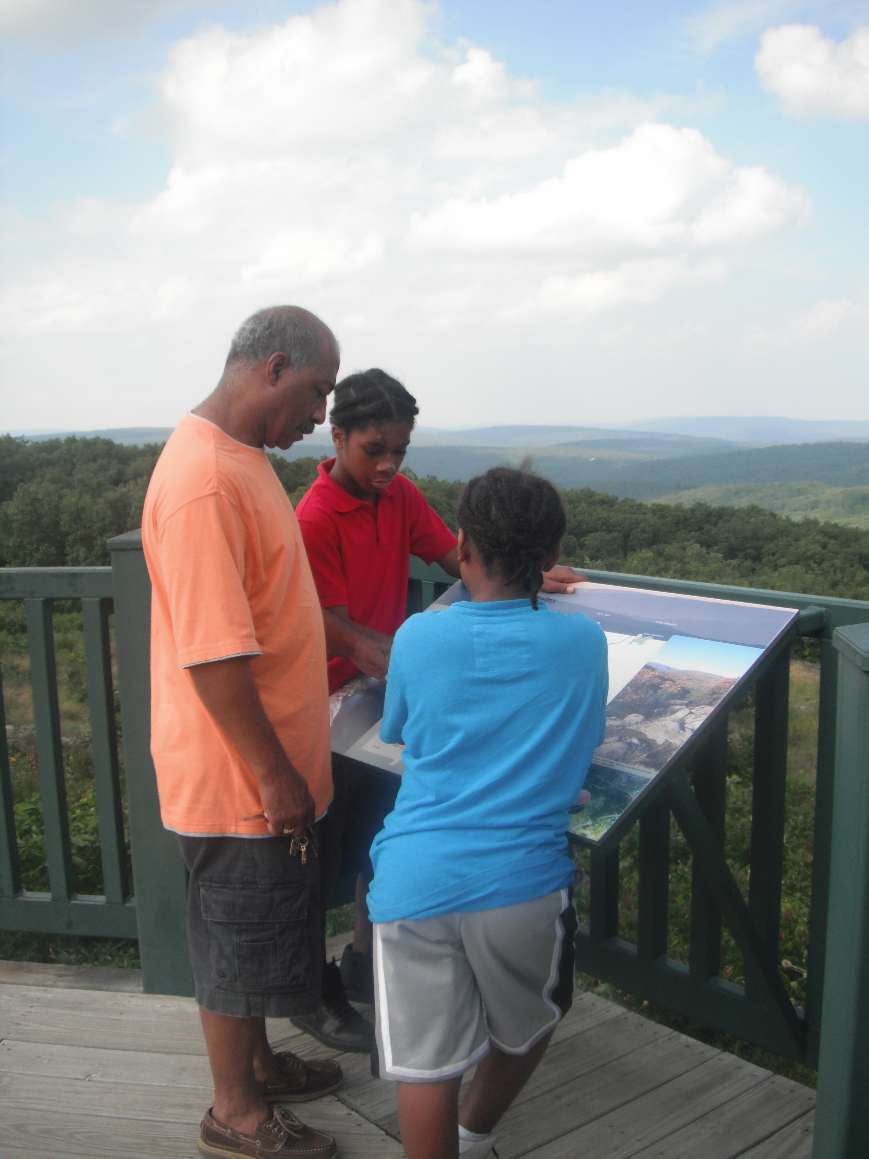 Three people looking at a map on a balcony