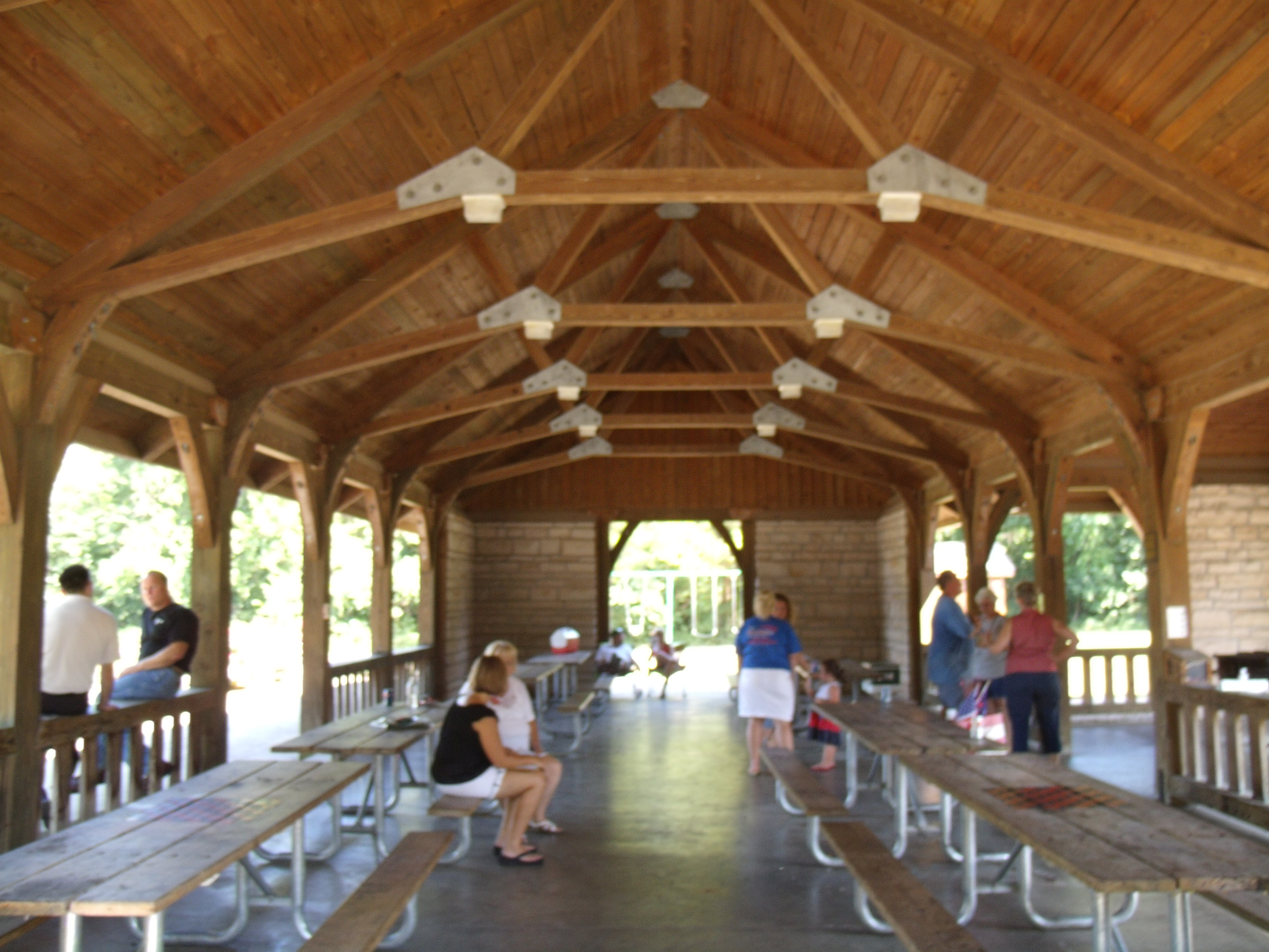 A group gathered around picnic tables under a pavilion