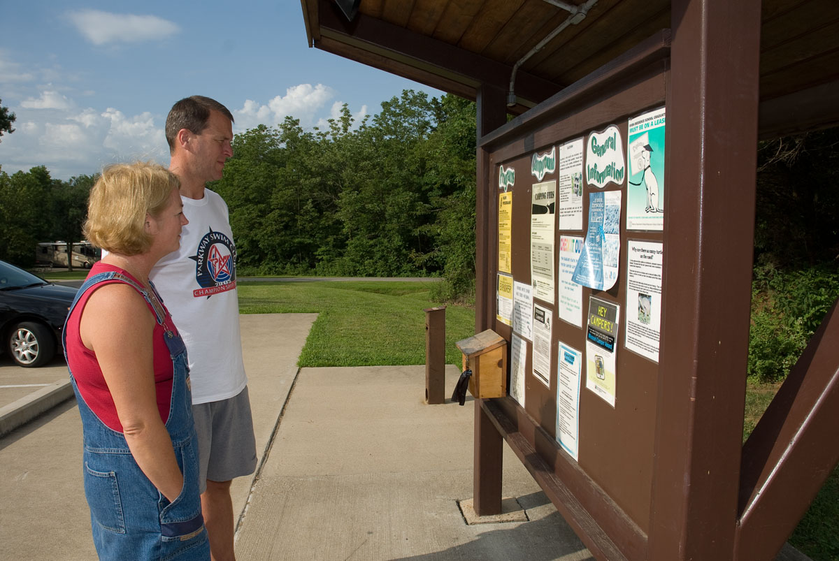 Two people looking at a bulletin board of park events