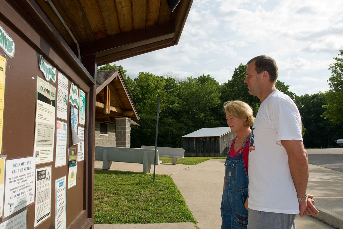 Two people looking at a bulletin board of park events