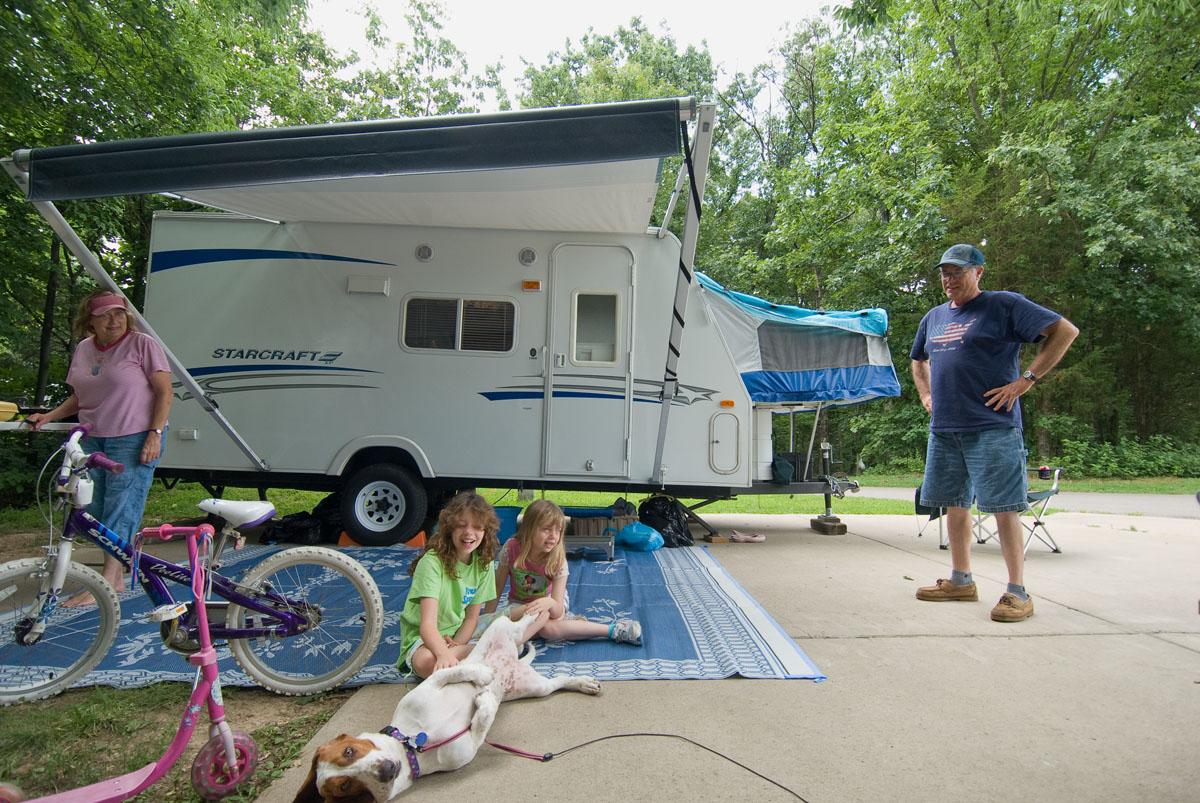 A family outside a camper with a dog