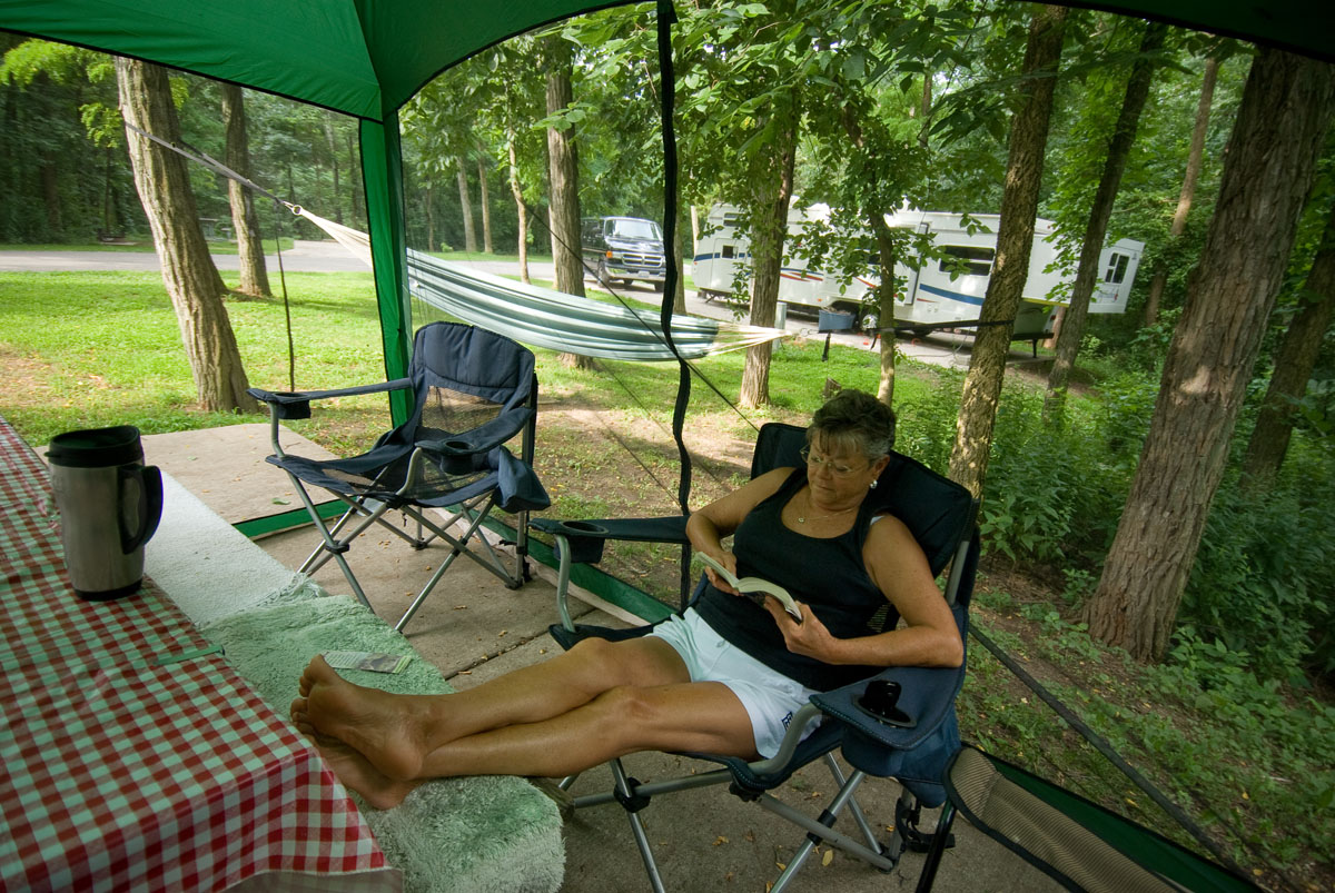 A woman reading on a lawn chair at a picnic site
