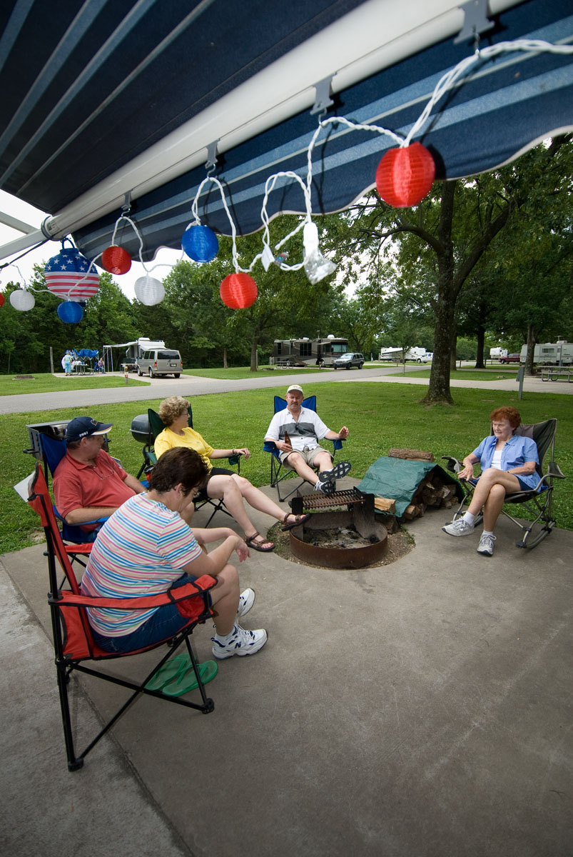 5 people sitting in lawn chairs by a fire pit