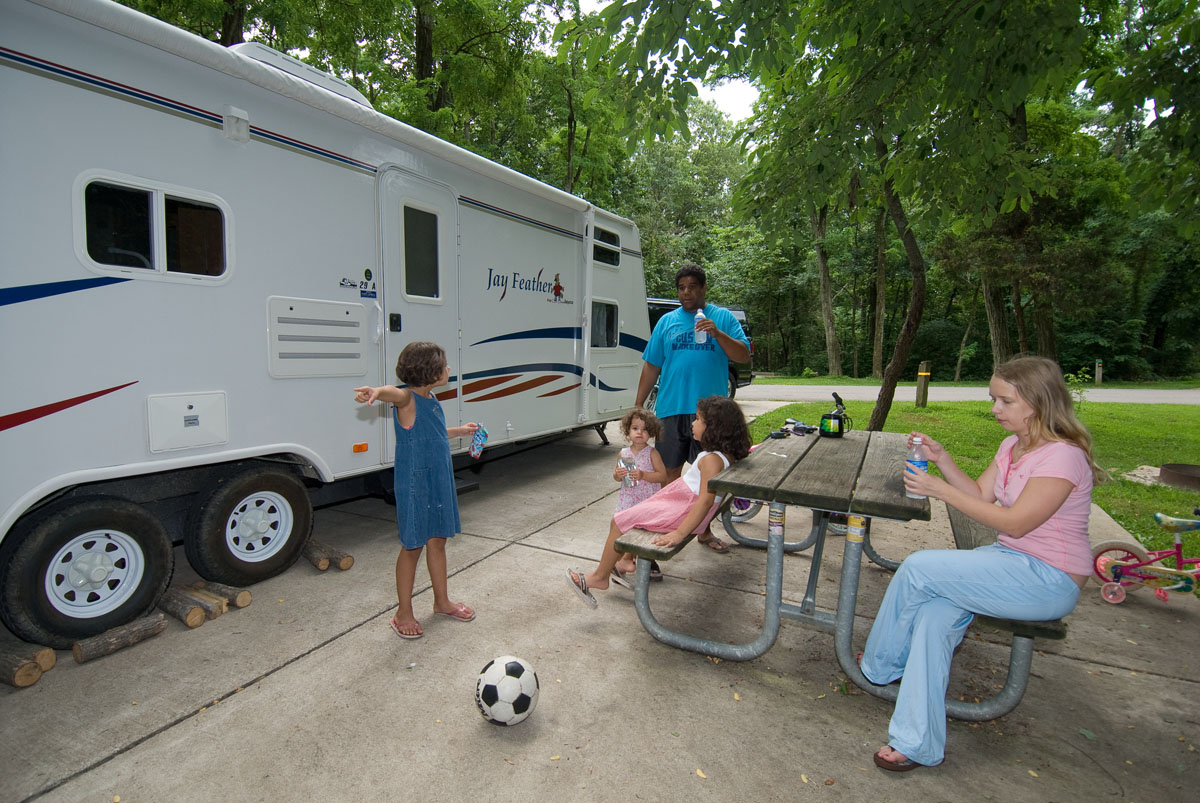 A family sitting at a picnic table outside a camper