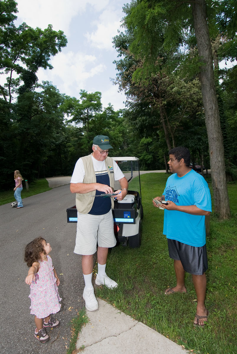 Two men and a child talking at a campsite next to a golf cart