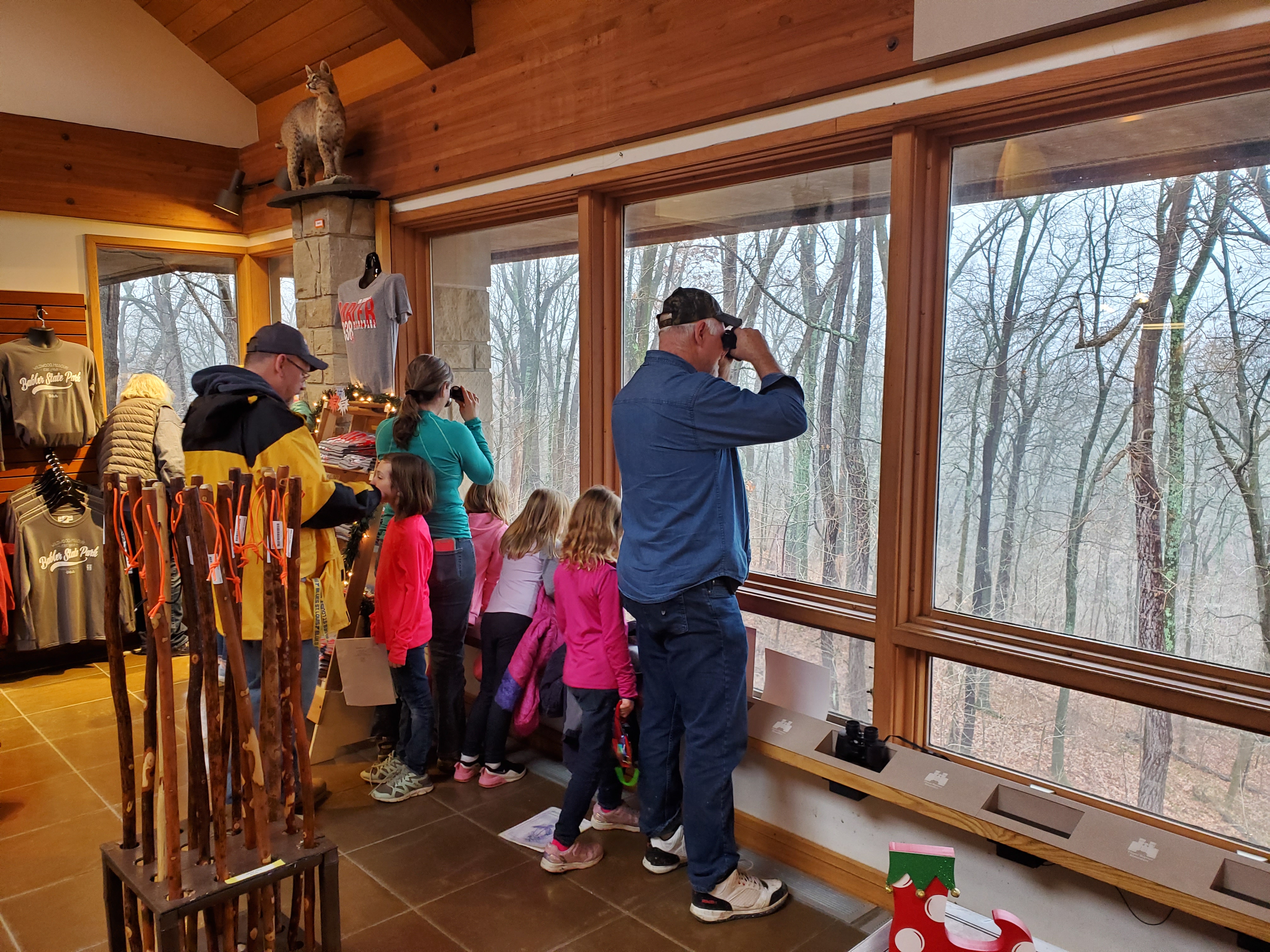 A group of people looking out the windows of the gift shop with binoculars