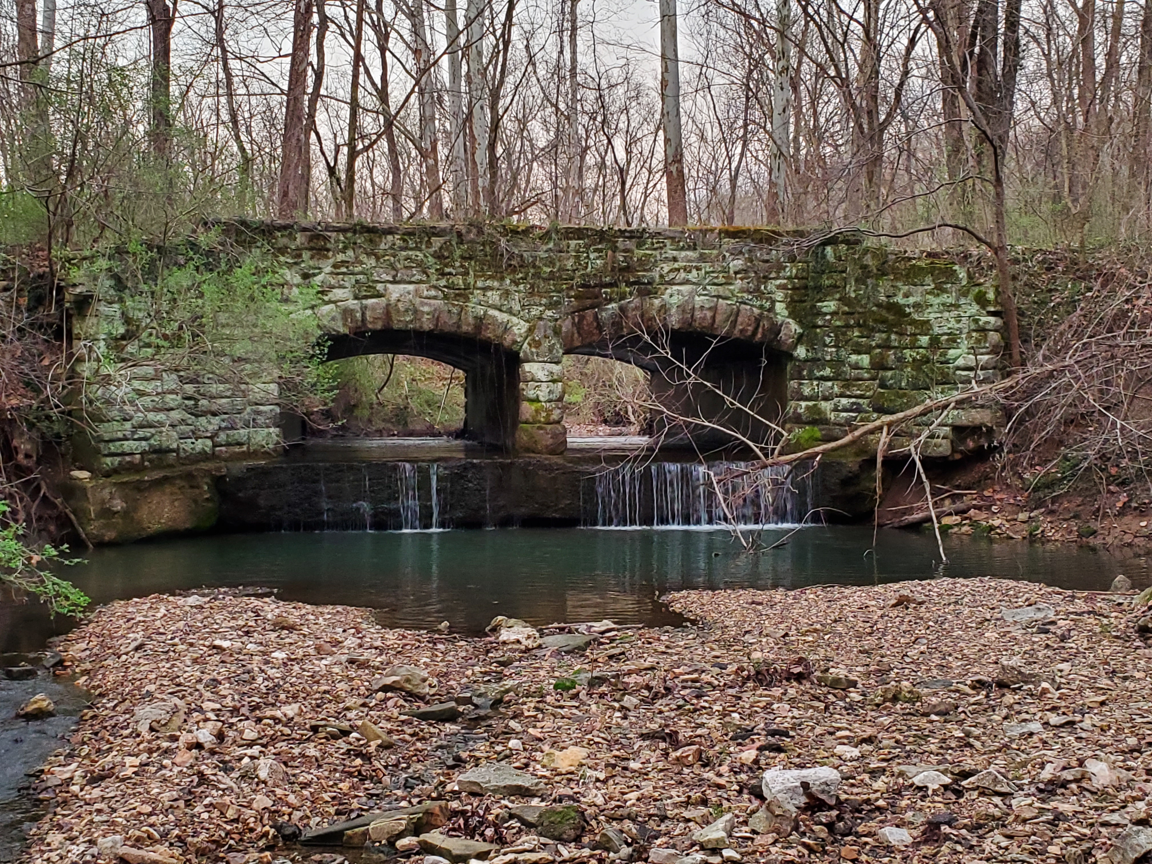 A mossy stone bridge over a small river