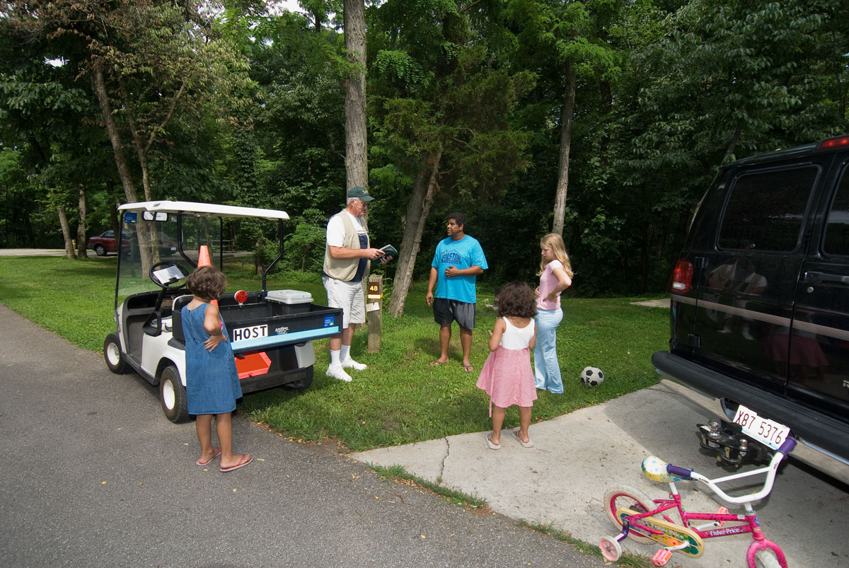 A family talking to a park ranger next to a golf cart