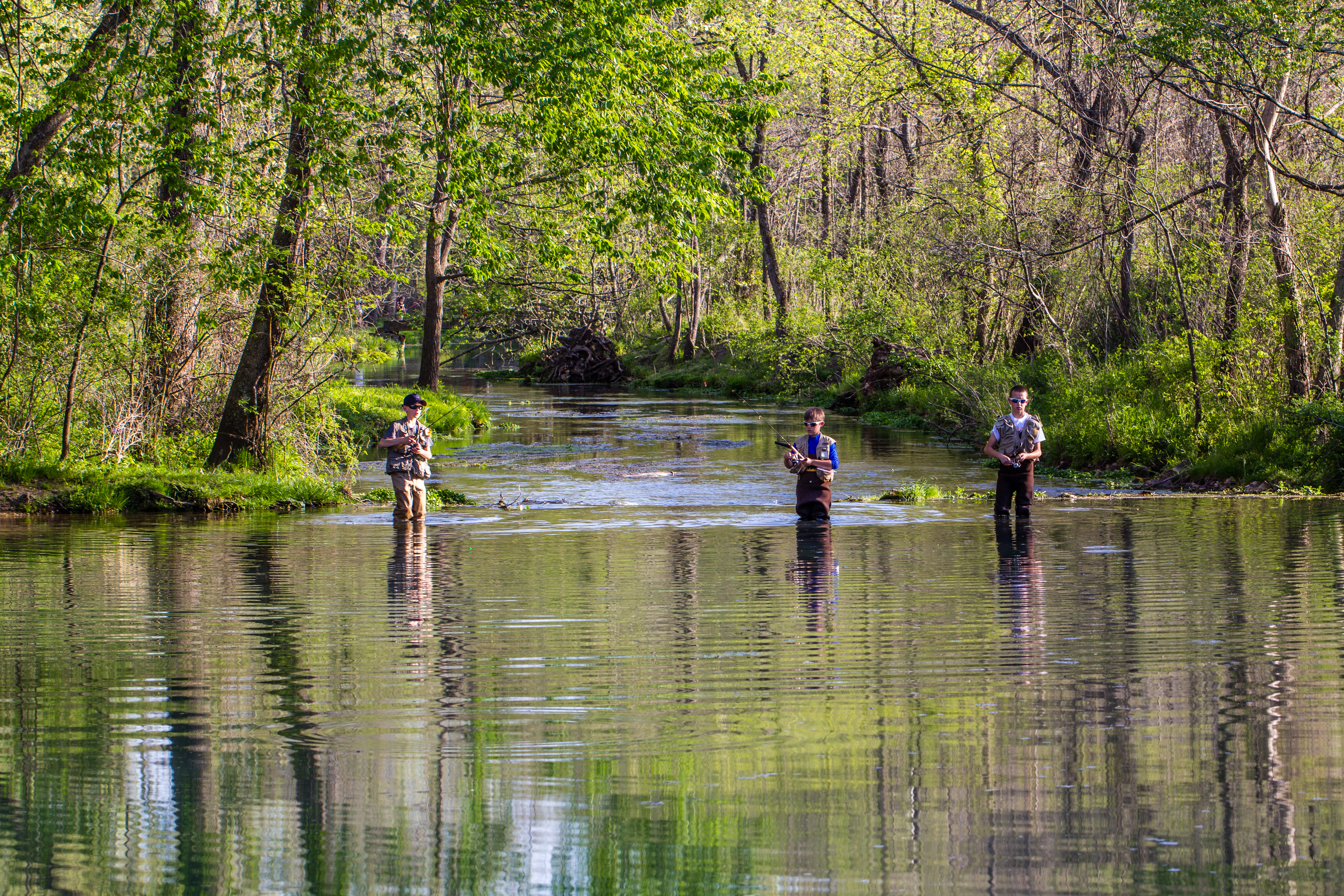 Three kids fishing in a shallow river