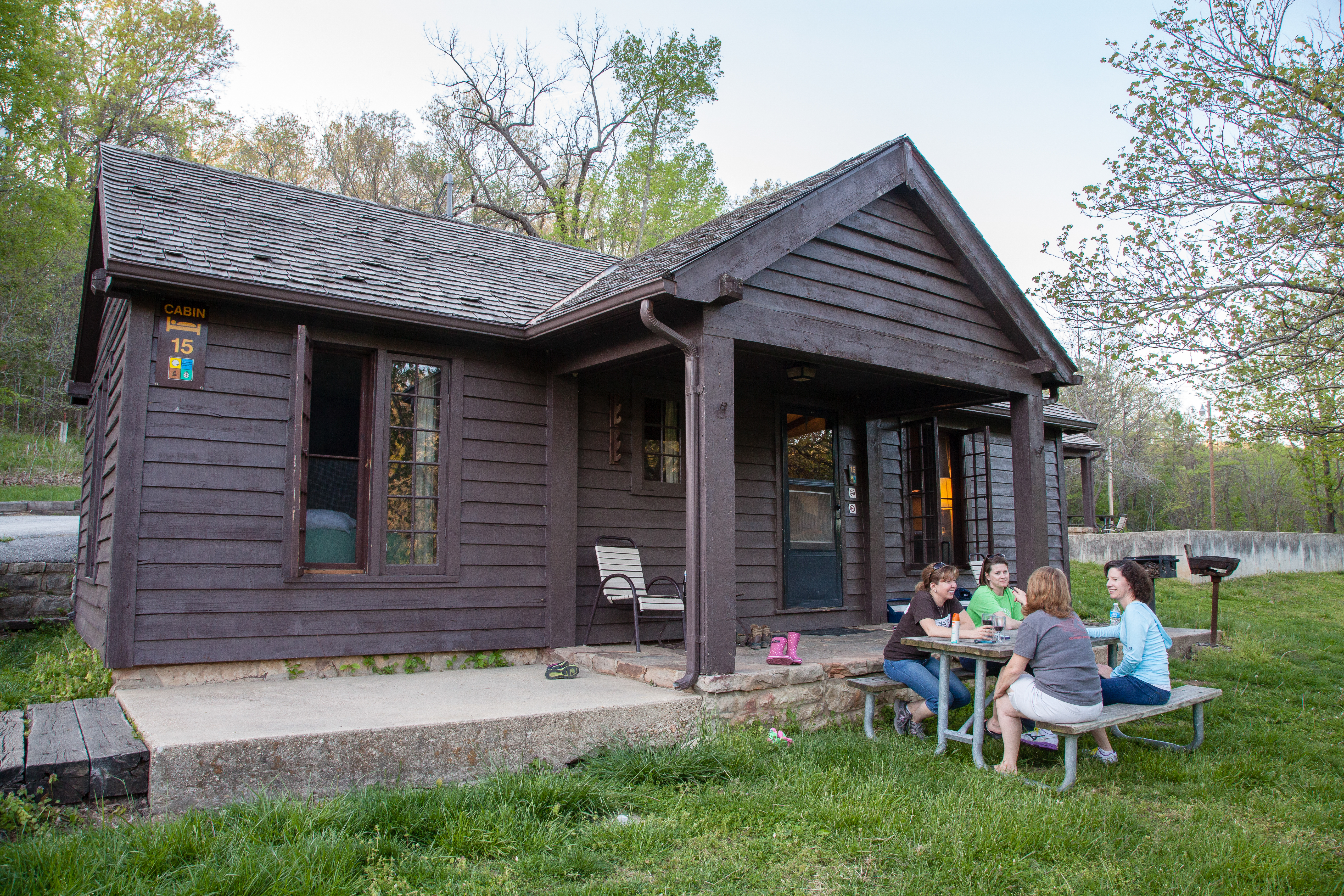 Four people sitting at a picnic table outside a cabin