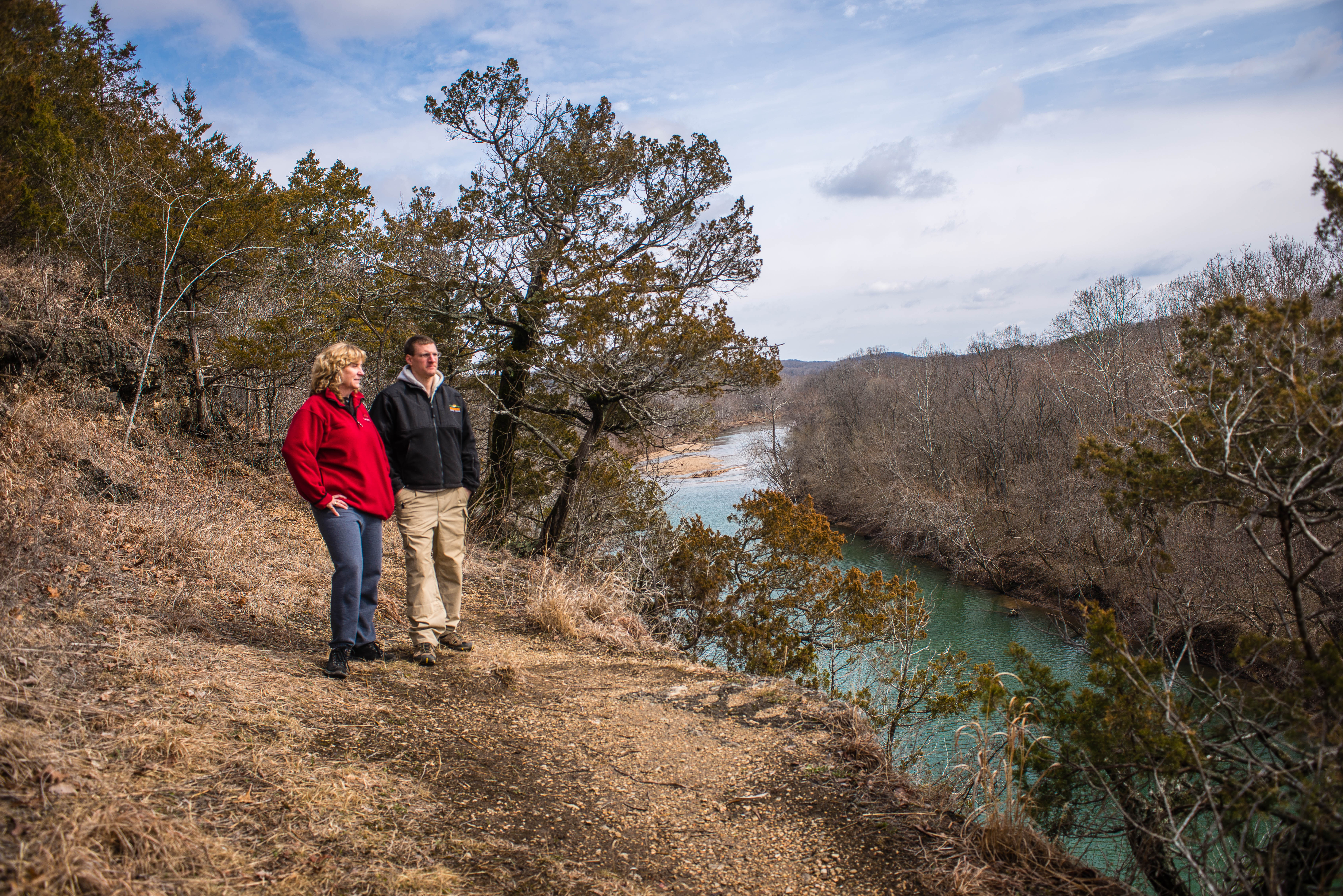 Two people standing on a cliff overlooking a river