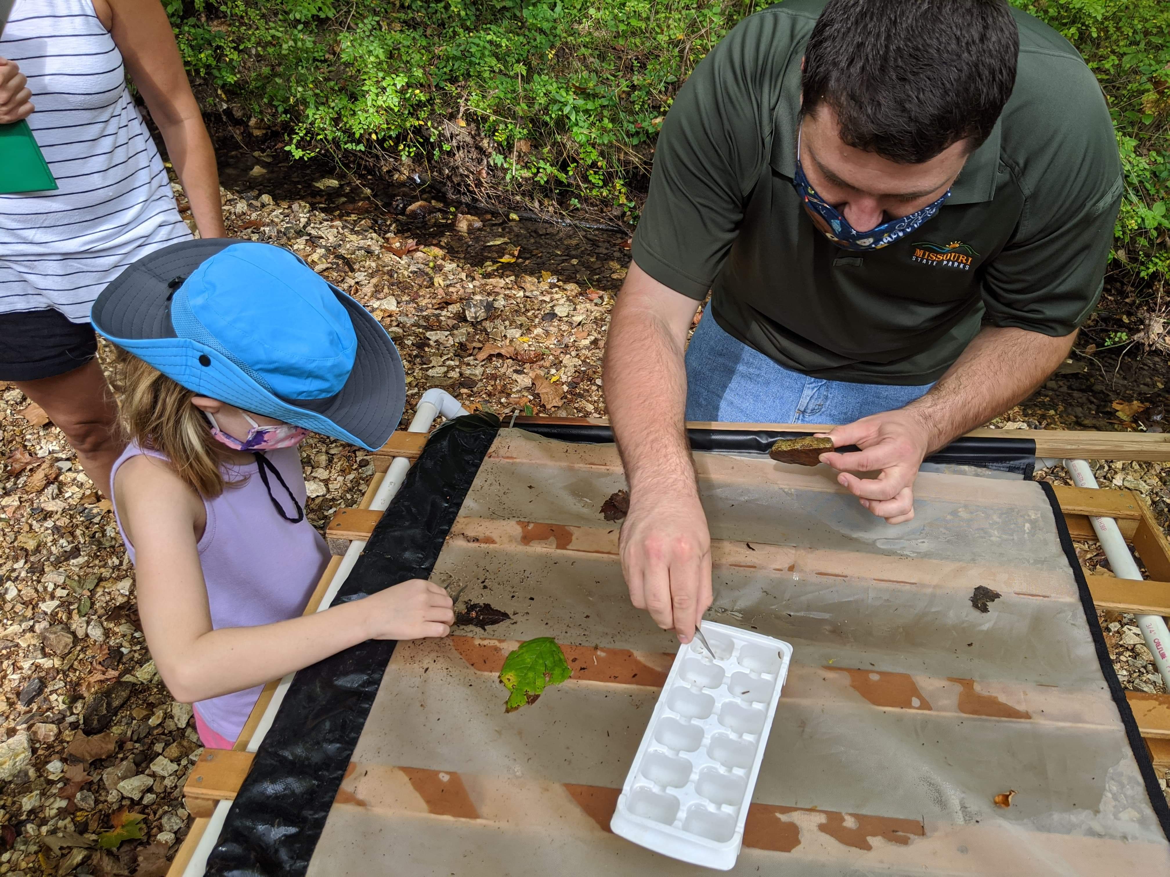 A park ranger and school kid doing a project outdoors